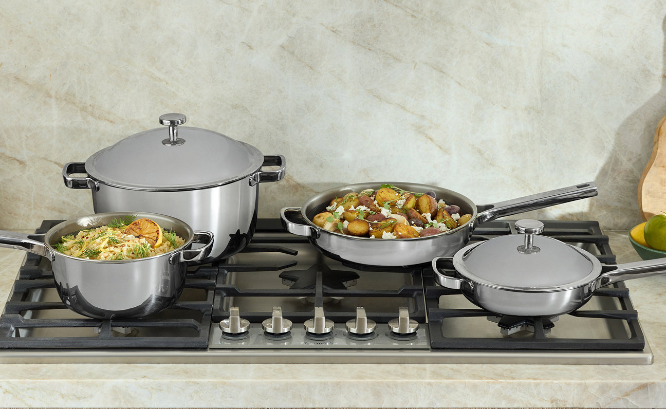 Set of titanium cookware on a gas stove with food inside